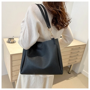 Close-up of black lychee texture tote bag with golden metal rings on a shoulder strap
