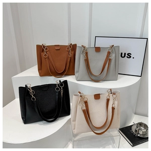 Dettaglio di quattro borse tote in pelle martellata in vari colori su un piedistallo bianco