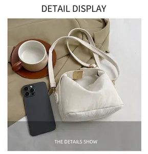 Detail view of white ruched PU leather bag with gold buckle and size reference to phone