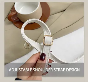 Detail of adjustable white leather shoulder strap with gold metal buckle on a handbag