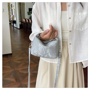 Detail of light grey wrinkled texture small crossbody bag with gold hardware and strap