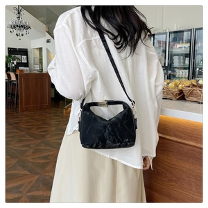 Detail of black soft PU handbag with pleated texture and pale gold metal hardware