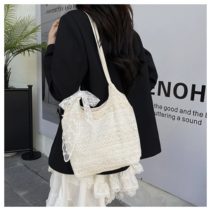 Detail of cream lace tote bag featuring intricate openwork patterns and bow accent