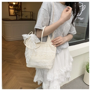 Close-up of cream white lace crochet tote bag with large decorative side ribbon bow
