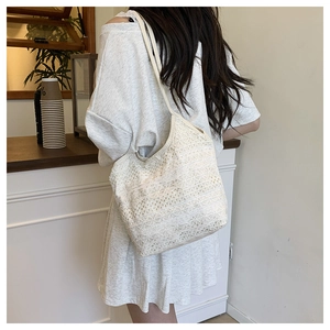 Close-up of cream white lace crochet tote bag with floral hollow texture on a model