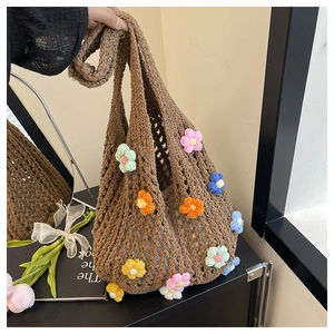 Close-up of handmade crochet tote bag featuring vibrant 3D floral accents and open knit texture