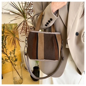 Close-up of a striped cotton-linen crossbody bag with adjustable strap and metal hooks