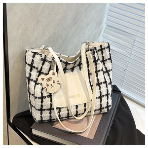 Dettaglio macro della borsa tote in tweed a scacchi con tasca in pelle e ciondolo