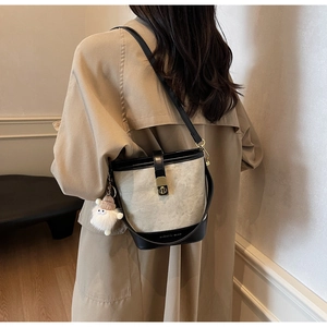 Détail du sac seau contrasté avec garniture en cuir et breloque peluche sur trench