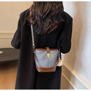 Détail du sac seau vintage en denim bleu avec bandoulière et fermoir en cuir marron