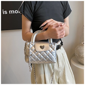Λεπτομέρεια ασημένιας καπιτονέ τσάντας με κούμπωμα καρδιά και μεταλλική αλυσίδα ώμου