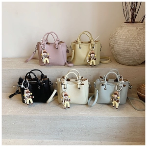 Close-up of leather crossbody bags with knotted handles and cute doll charms in five colors