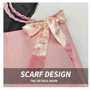 Detail of pink houndstooth tote bag featuring a floral silk scarf handle and woven strap
