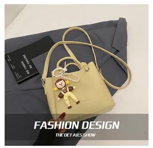 Detail of yellow lychee leather bucket bag with fashion stamp and pearl doll charm