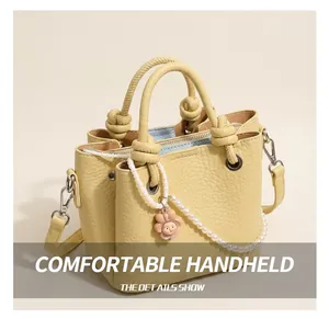 Detail of light yellow lychee grain leather bucket bag with knotted handle and zip closure