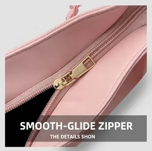 Close-up of smooth golden metal zipper and premium pink leather texture on tote bag
