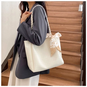 Detail view of a white large tote bag with a floral scarf bow and woven shoulder strap
