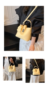 Détail du sac seau en cuir jaune grainé avec poignée supérieure et charm chiot