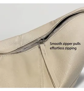 Nahaufnahme von glattem Silberreißverschluss und Lychee-Leder an der beigen Umhängetasche