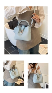 Détail du sac seau bleu clair à motif litchi avec fermoir argenté et breloque chien
