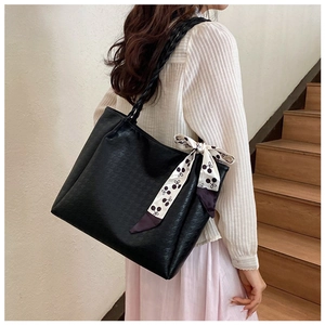 Large black textured tote bag with cherry print scarf detail worn by a model