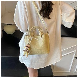 Light yellow lychee textured bucket bag with cute cartoon doll charm and fashion print