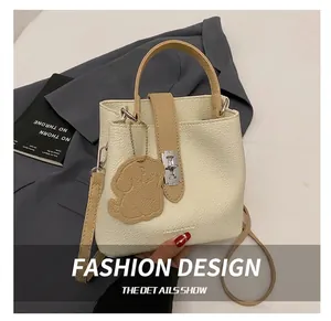 Détail d'un sac seau beige en cuir grainé avec fermoir argenté et breloque en forme de chien