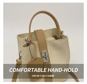 Détail du sac seau beige à texture grainée avec poignée marron et fermoir argenté