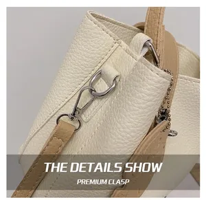Détail du crochet métallique argenté et de la bandoulière en cuir grainé du sac crème