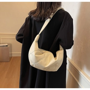 Detailansicht einer großen cremefarbenen Hobo-Tasche mit Diagonalnähten an einem Model