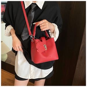 Détail du sac seau en cuir grainé rouge avec boucle argentée et charm de chien assorti