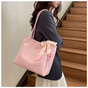 Detail of pink leather tote bag with woven strap and floral scarf bow on stairs