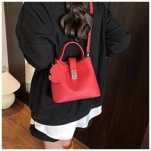 Détail d'un sac à main en cuir rouge avec fermoir argenté et breloque chien