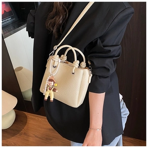 Detail of beige litchi leather bucket bag with knotted handles and pearl charm