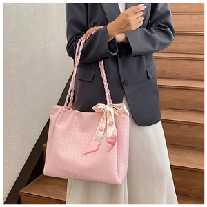 Pink tote bag detail with textured finish, woven handles, and decorative floral scarf knot