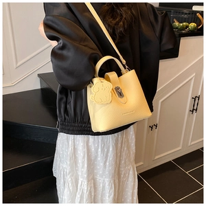 Détail du sac seau en cuir grainé beige avec fermoir en métal argenté et breloque chien