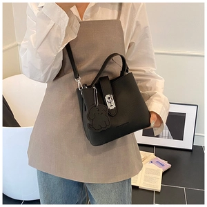 Détails du sac seau noir en cuir grainé avec fermoir rotatif argenté et porte-clé chien