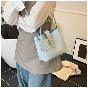 Détail du sac seau en cuir bleu clair à motif litchi avec breloque chien et ferrures argentées