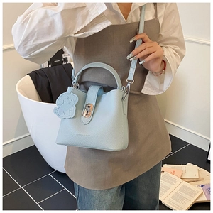 Détail du sac seau bleu clair avec fermoir doré et breloque en forme de chien blanc