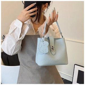 Détail du sac seau bleu clair avec fermoir rotatif argenté et charm chien pour 2025