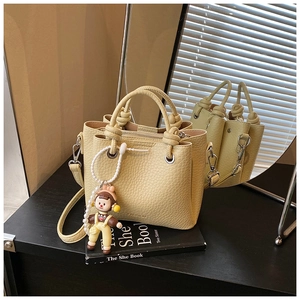 Detailed view of yellow litchi grain leather bucket bag with cute cartoon charm