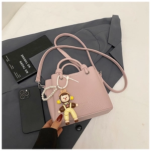 Detailed macro view of pink litchi leather bag with pearl doll charm and fashion embossing