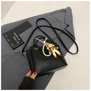 Detail of black lychee leather crossbody bag with fashion print and pearl chain charm