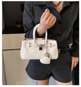 Detail of white patent leather handbag with silver lock and heart charm