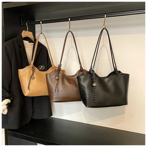 Detailed view of leather tote bags in tan, brown, and black with woven knot charms