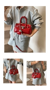 Close-up of red patent leather handbag with metallic lock and pearl chain strap detail