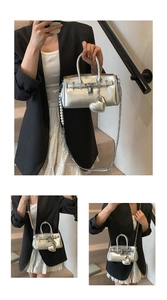Detail of silver metallic handbag featuring heart pendant and pearl chain strap
