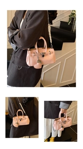 Detail of pink fashion handbag with pearl chain strap and heart charm in indoor setting
