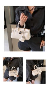 Close-up of beige patent leather handbag with metal lock and pearl chain strap