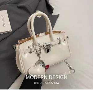 Detail shot of the white leather handbag featuring silver hardware locks and heart charm